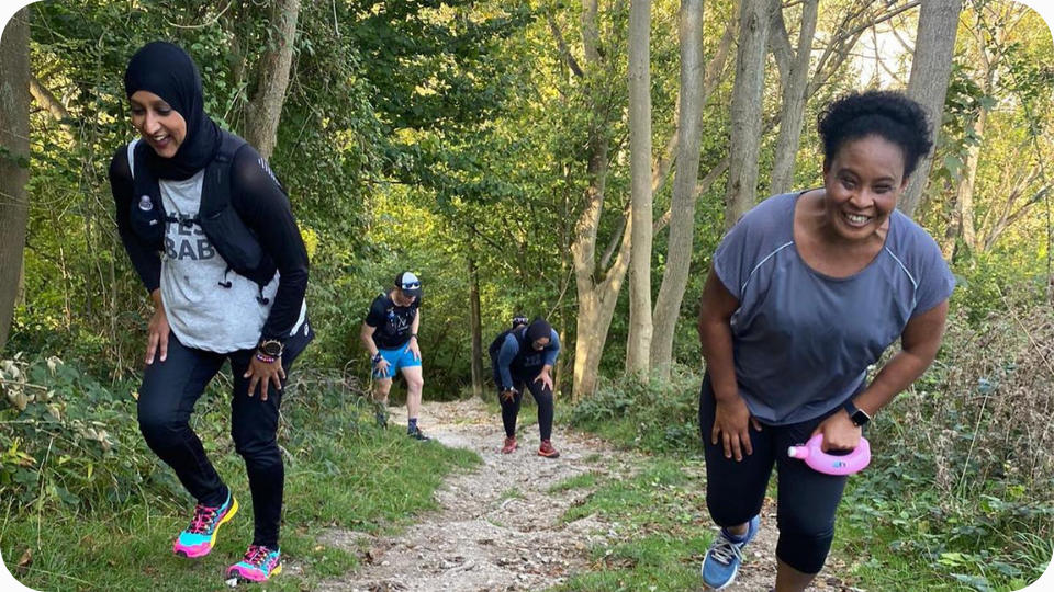 Female trail runners climbing a steep hill in Wendover Woods, Buckinghamshire.